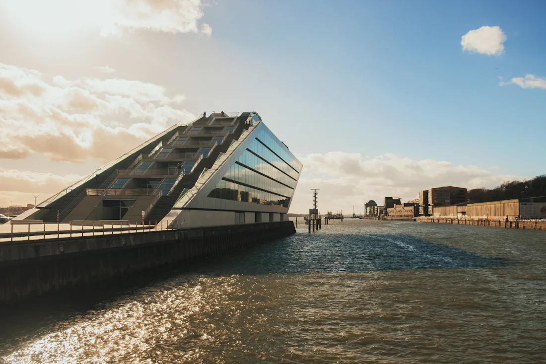 Das Bürogebäude Dockland am Elbufer in Hamburg-Altona, davor die Kaimauer und die Elbe im Abendlicht