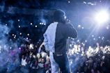 Eljay performing on stage with futuristic neon lights and a packed crowd.