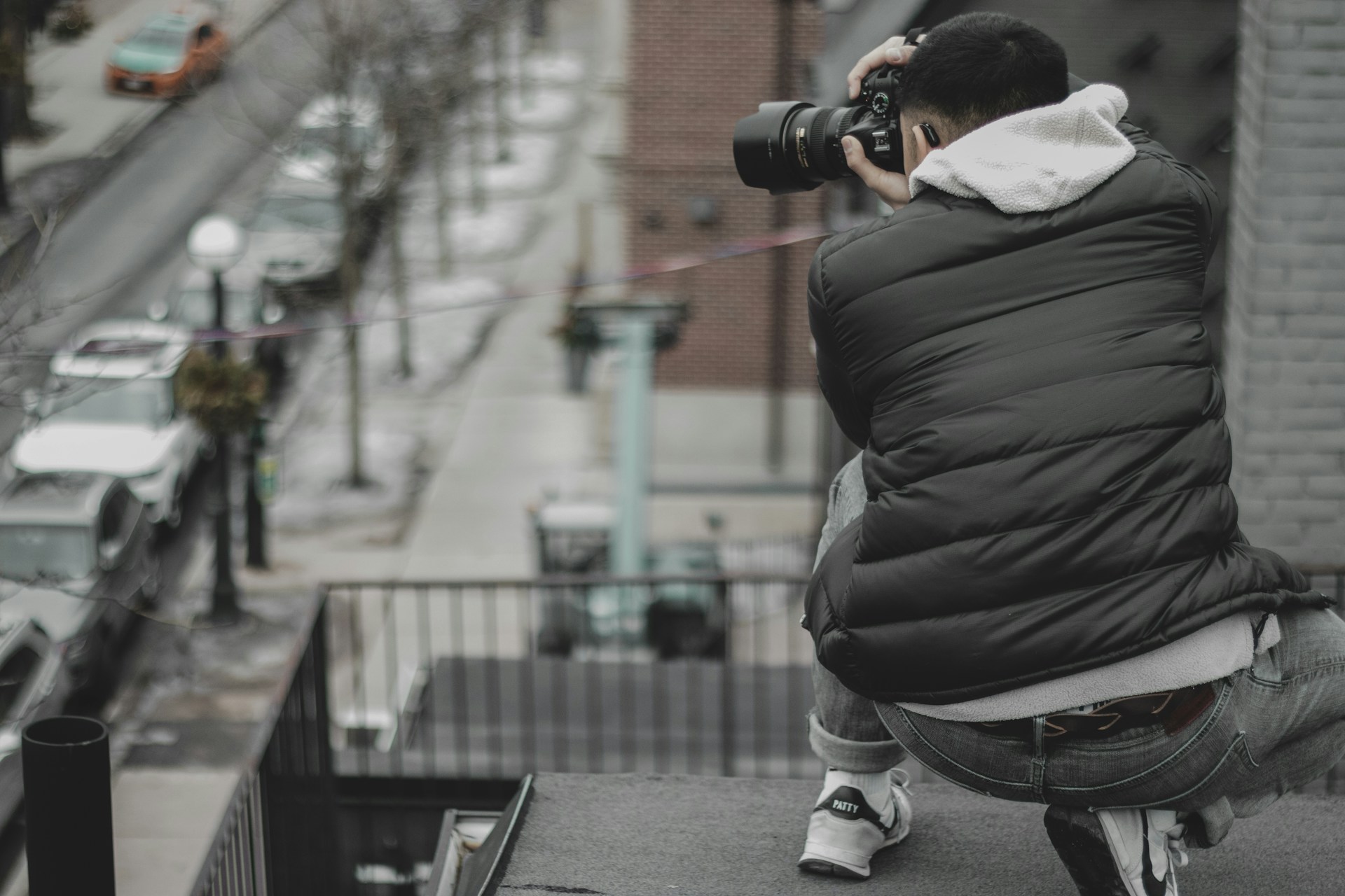 man taking photo of street on rooftop
