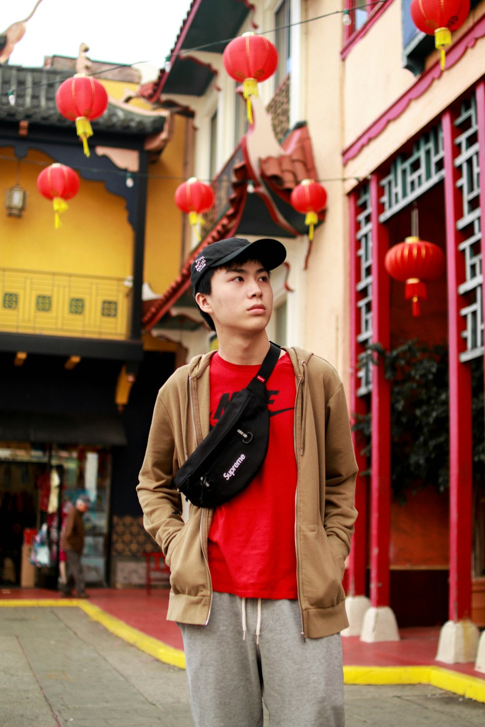 man wearing beige jacket and red crew-neck top walking on street