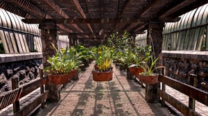 An outdoor walkway is covered by a wooden pergola. Large, rust-colored metal pots are suspended from the beams, each containing vibrant green plants. The sunlight filters through the slatted roof, casting shadows on the stone pathway. On either side, there are stone walls with slightly curved glass panels fixed above.