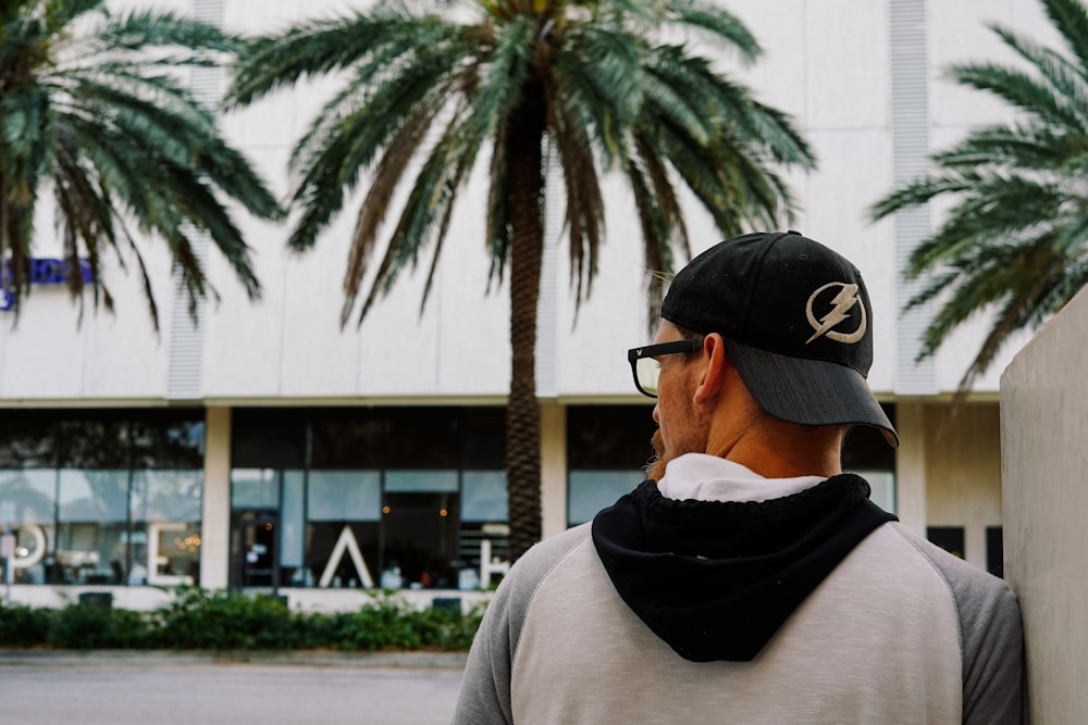 man wearing black and white hoodie and black and white snapback walking on street druring daytime