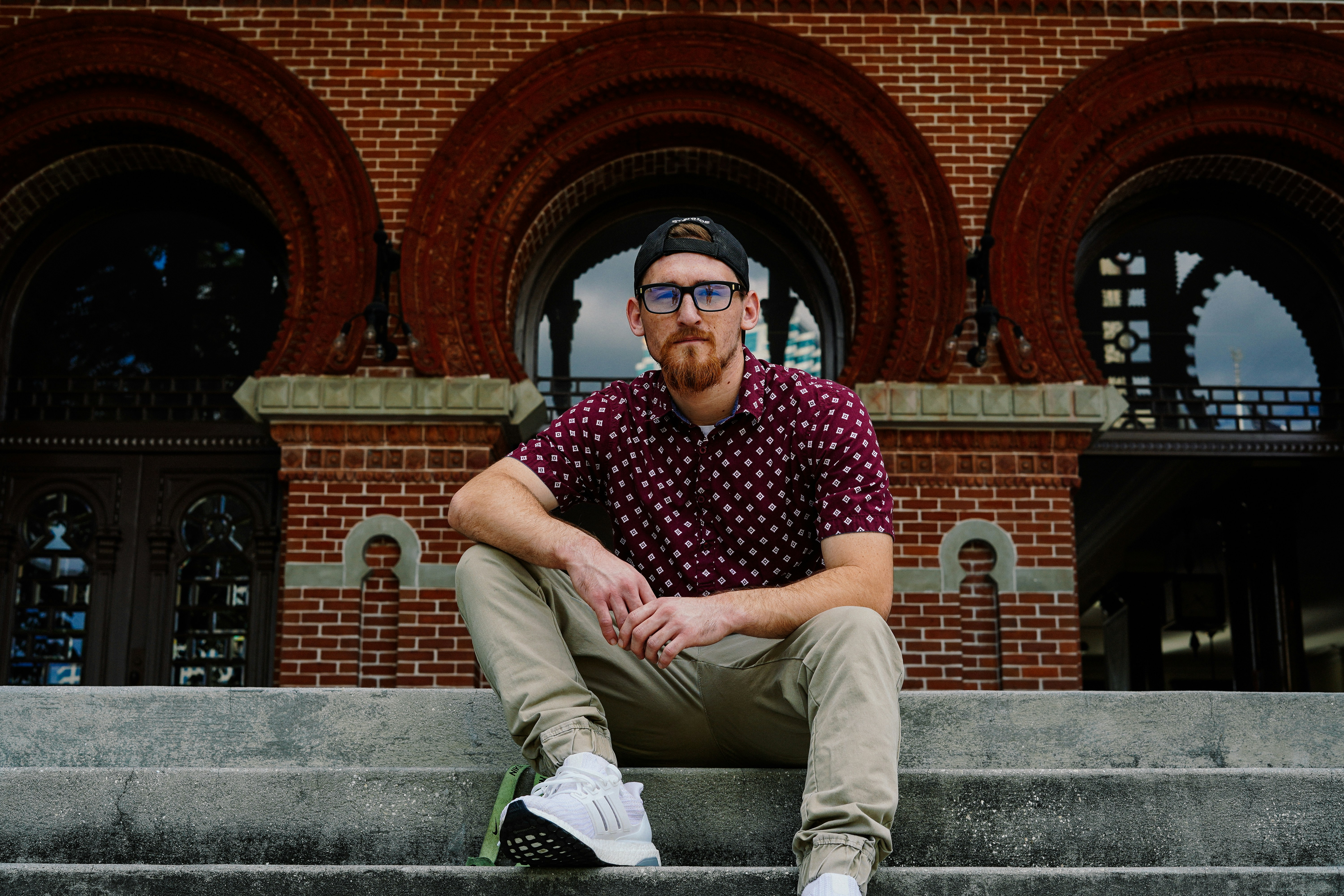man in red polo shirt sitting on stairs