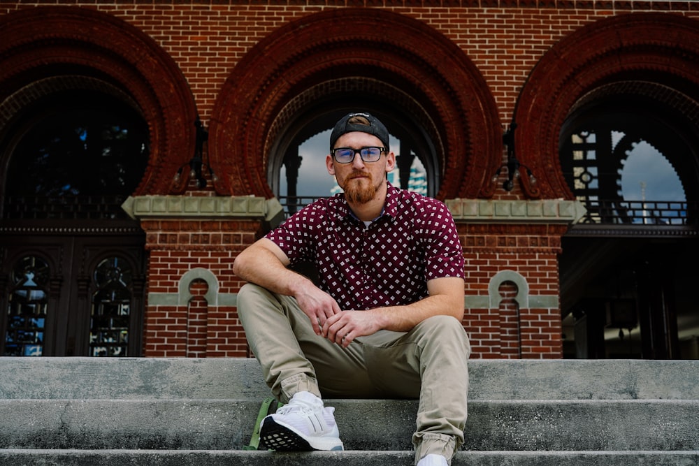 man in red polo shirt sitting on stairs