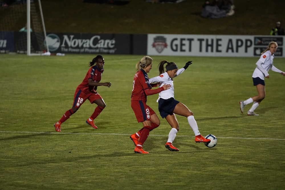 women playing soccer of grass field