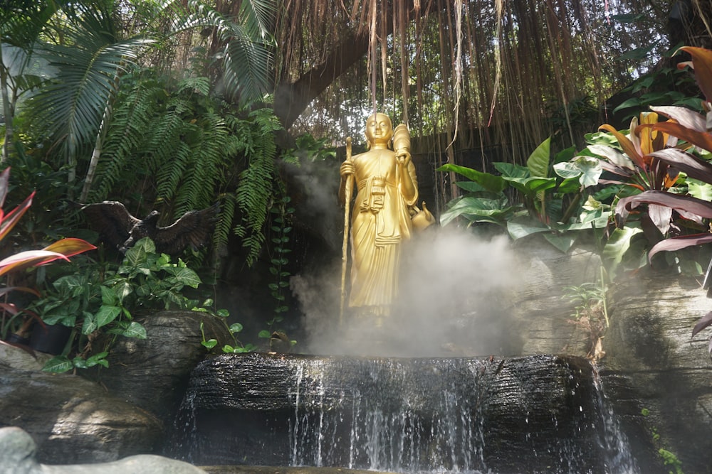 gold buddha beside fern plant