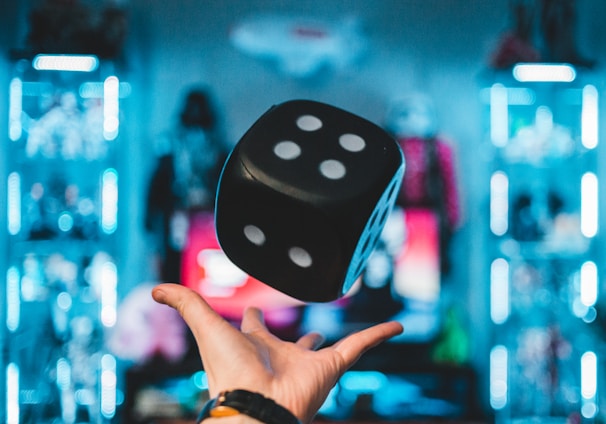 person's left palm about to catch black dice