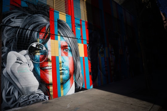 A vibrant mural on a city wall showing a powerful portrait blending graffiti and realism.