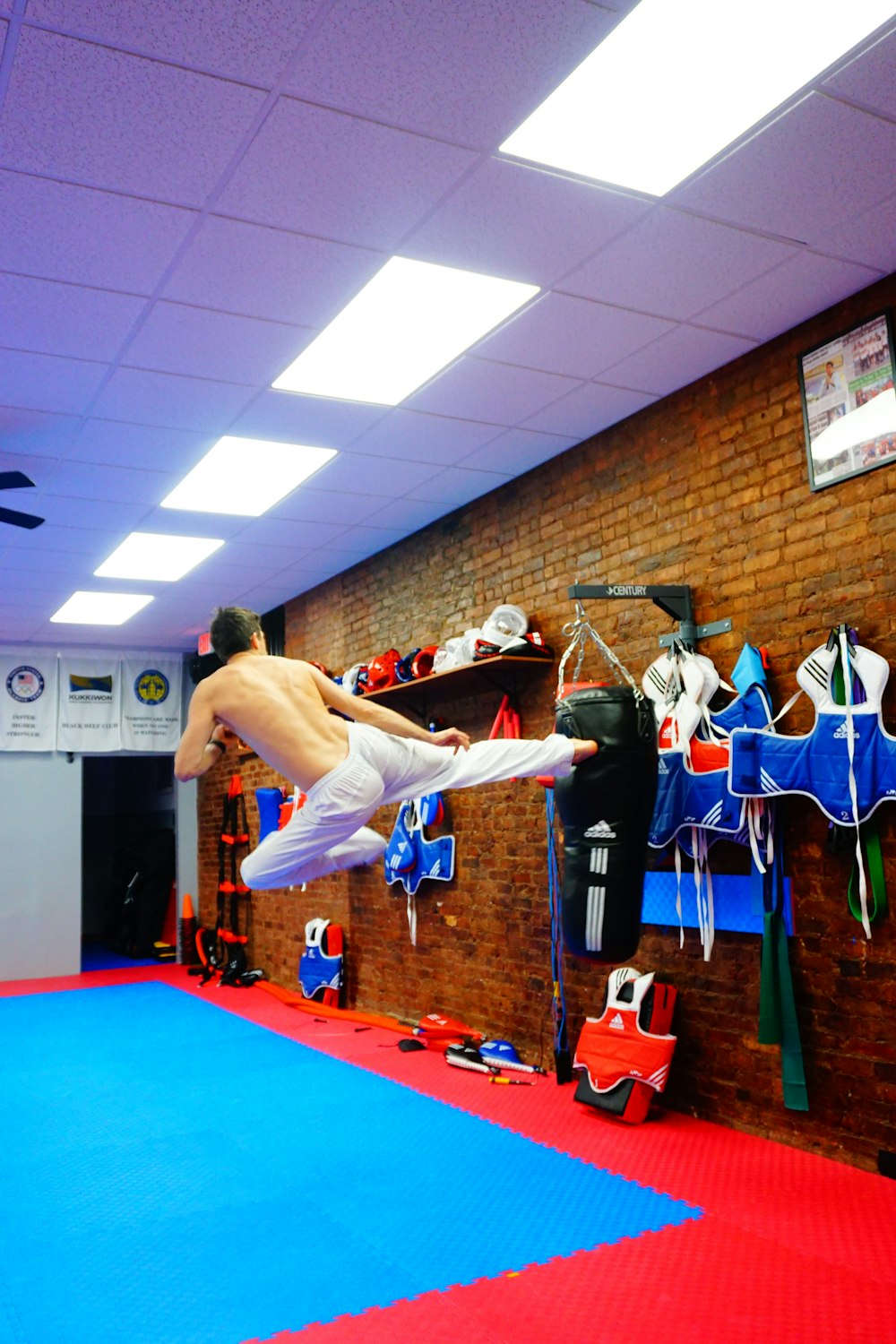 man kicking black punching bag