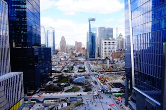 Group of professionals discussing plans outdoors at a development site with city skyline in the background.
