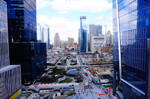 Group of professionals discussing plans outdoors at a development site with city skyline in the background.