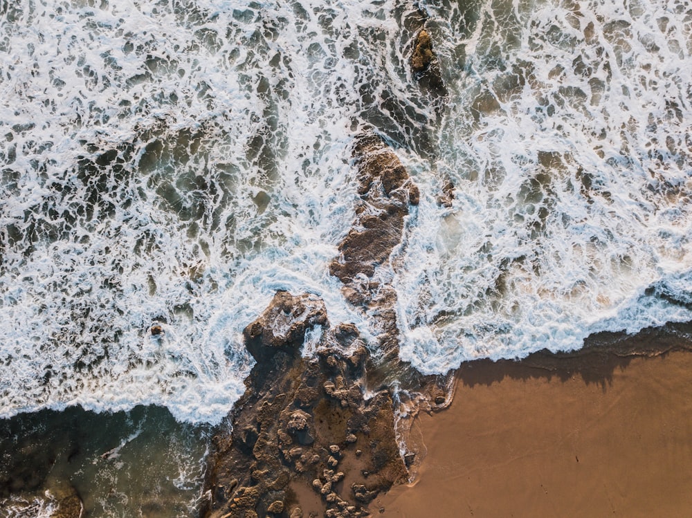 water hitting rocks on shore during daytime