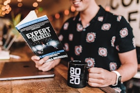 smiling man reading book while holding mug