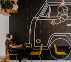 man wearing headphone using laptop while sitting beside table inside cafe