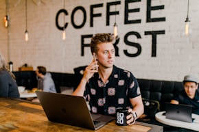 man holding phone white using MacBook