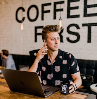 man holding phone white using MacBook