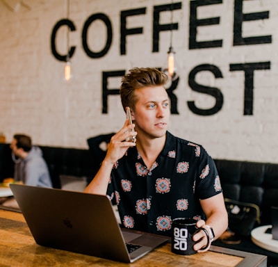 man holding phone white using MacBook