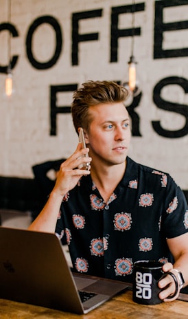 man holding phone white using MacBook