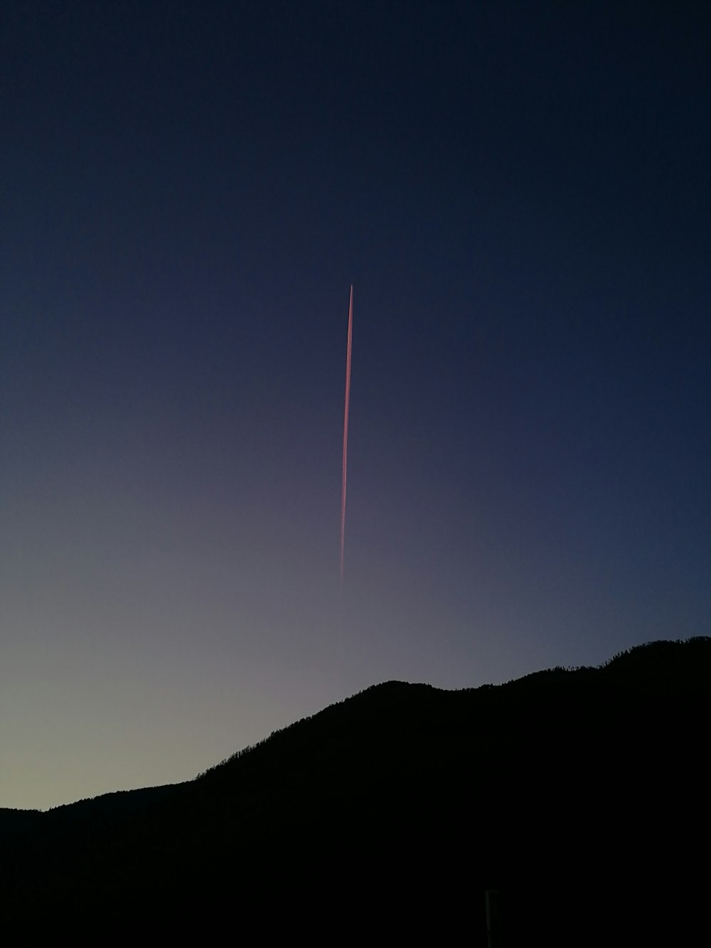 a plane is flying in the sky over a hill