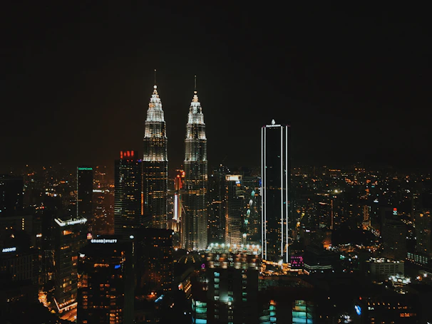 Nighttime city skyline of Kuala Lumpur with vibrant lights and towering skyscrapers.