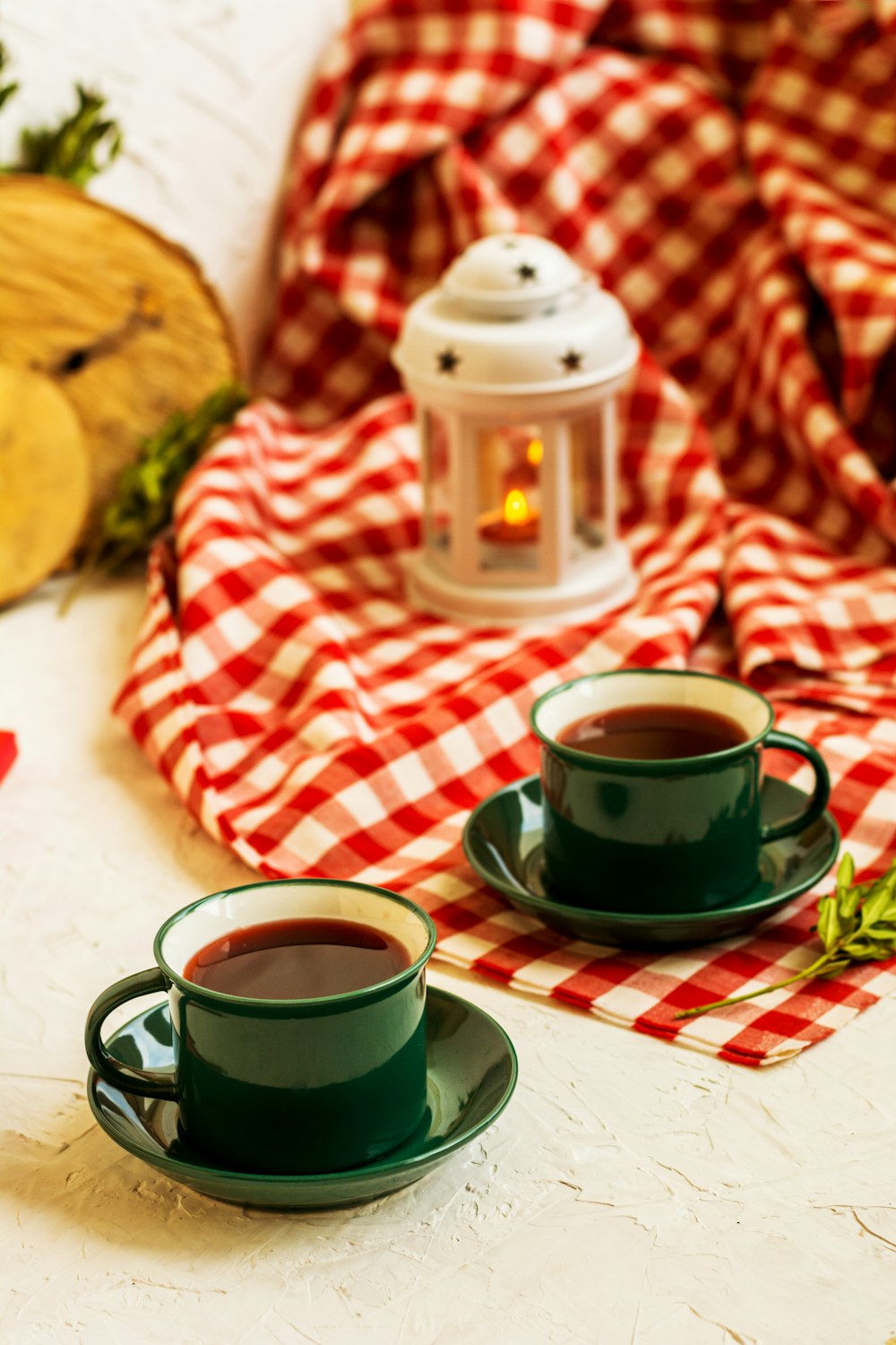 two green tea cups half full near red blanket and lamp