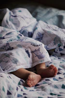 Baby's feet in pastel-colored socks and Hoko shoes resting on a cozy knitted blanket.