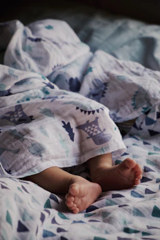 Tiny baby onesies and cozy booties arranged on a soft pastel blanket.