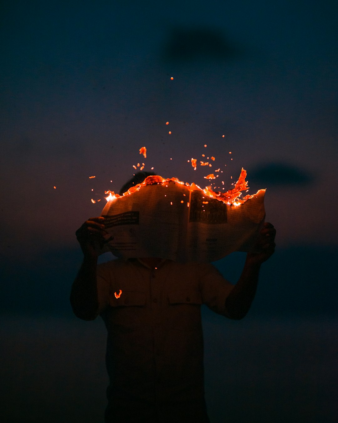 man holding burning paper at night