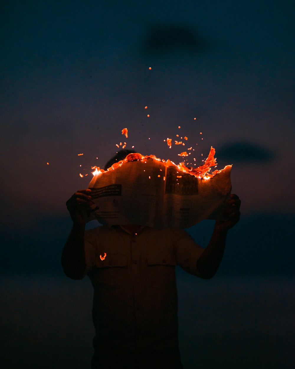 man holding burning paper at night