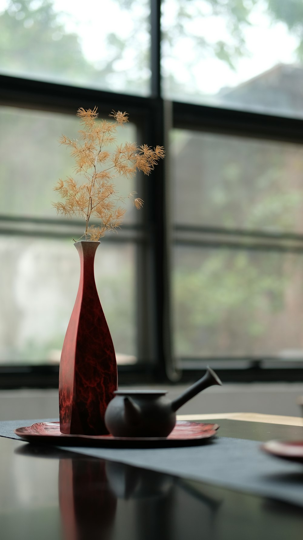 white flower on red vase beside teapot