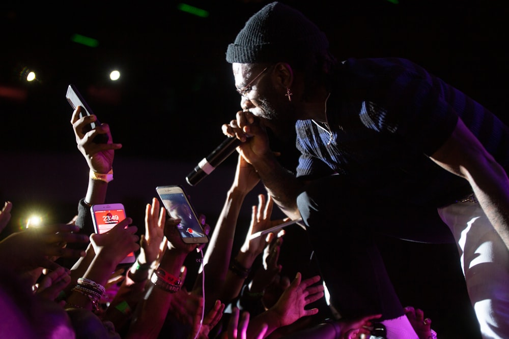 homme portant une casquette en tricot noir tenant un microphone sans fil noir