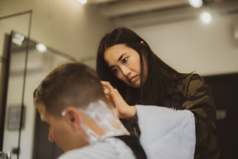 woman holding straight razor shaving man hair head