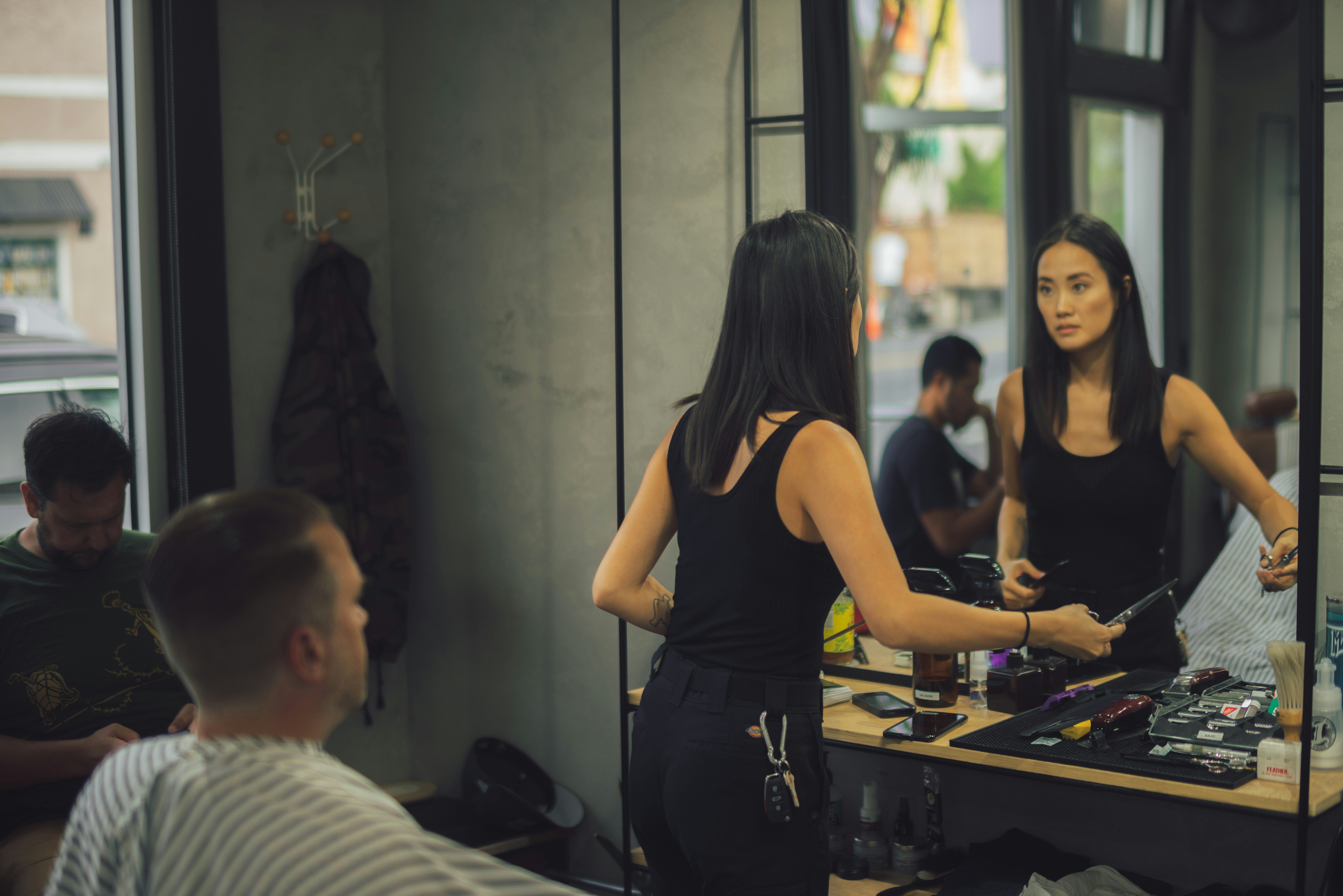 Stylist performing a precision haircut in a well-lit salon, dark background, professional scissors visible