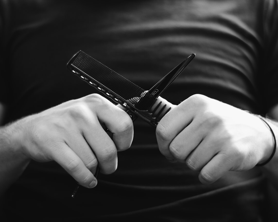 grayscale photography person holding scissors and hair comb