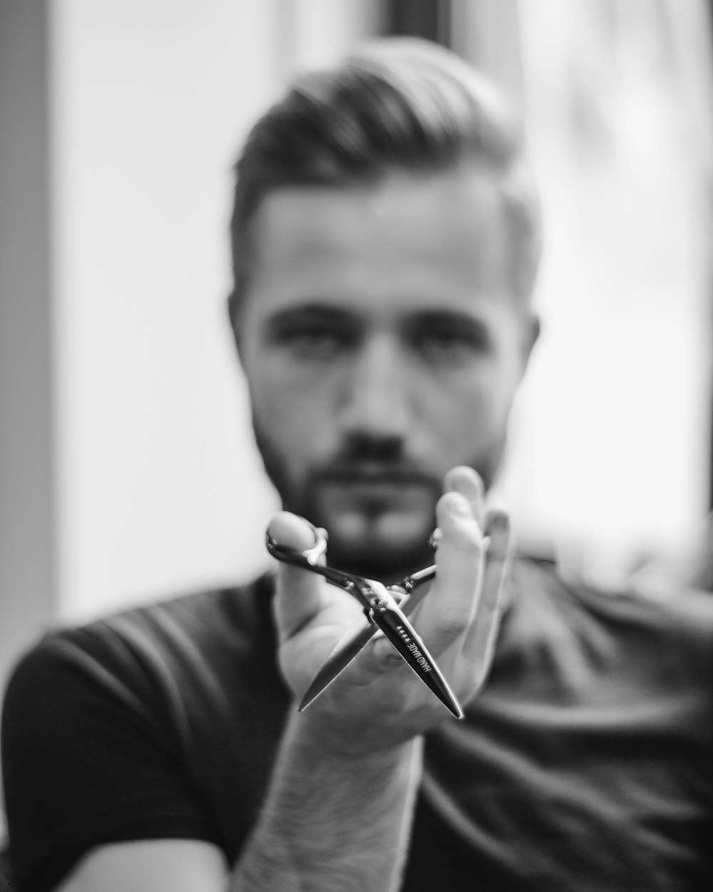 shallow focus photo of man holding scissors