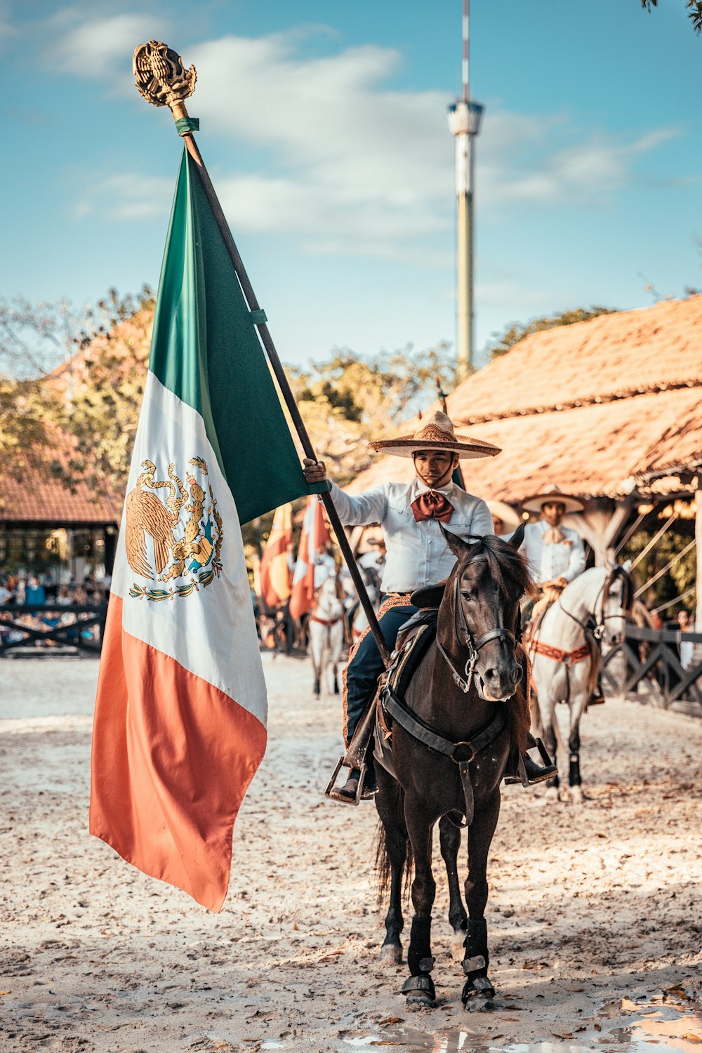 man riding on horse while holding flag of Mexico