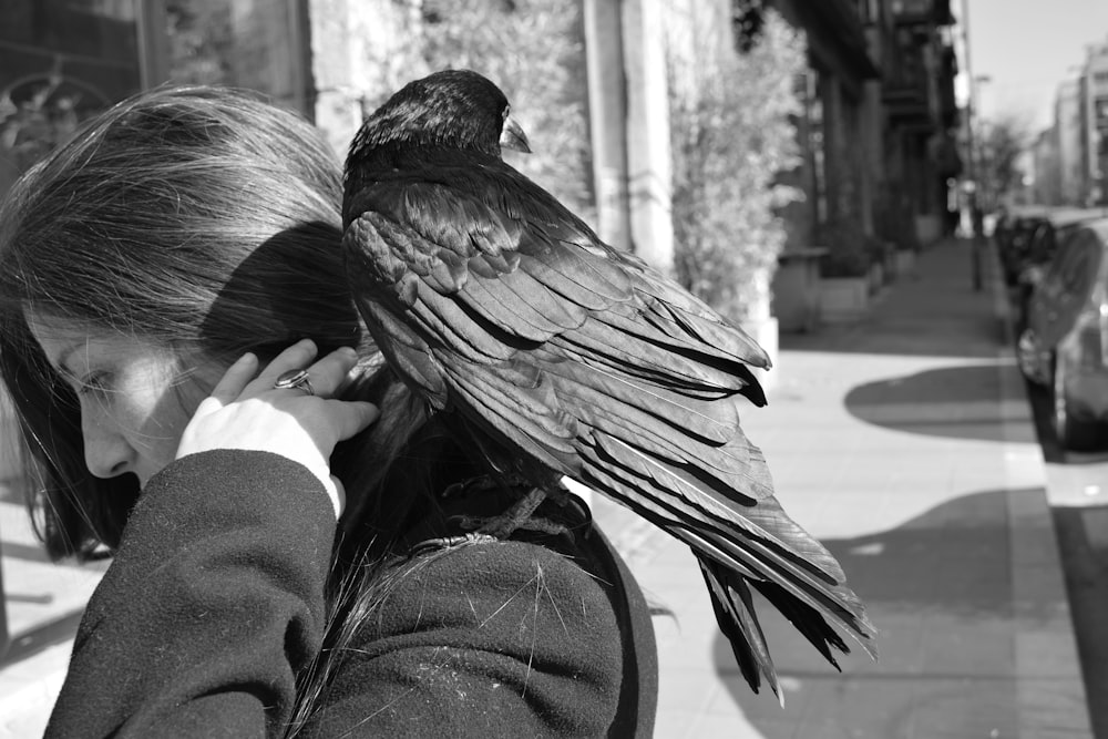 crow perched on woman's shoulder grayscalle photo