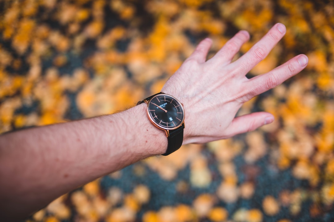 shallow focus photography person showing round gold-colored analog watch