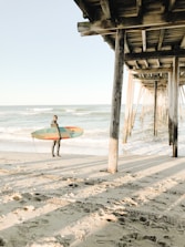 A surf coach providing feedback to a surfer on the beach.