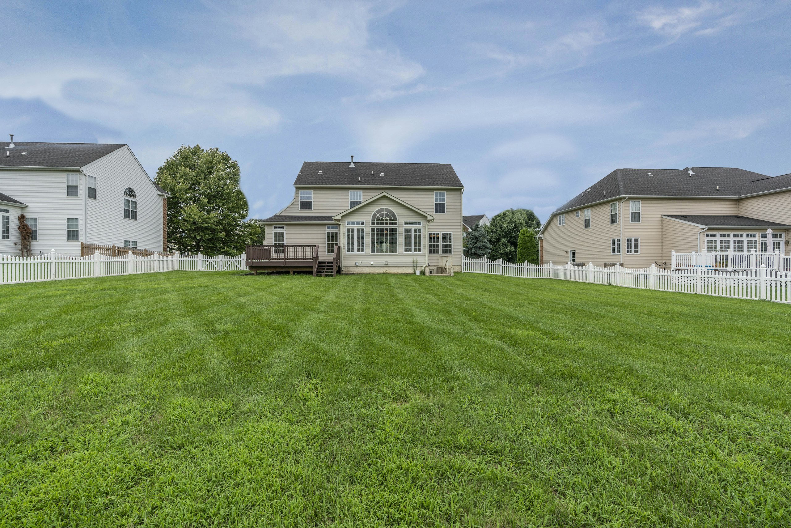 three 2-storey houses with fences and grass field