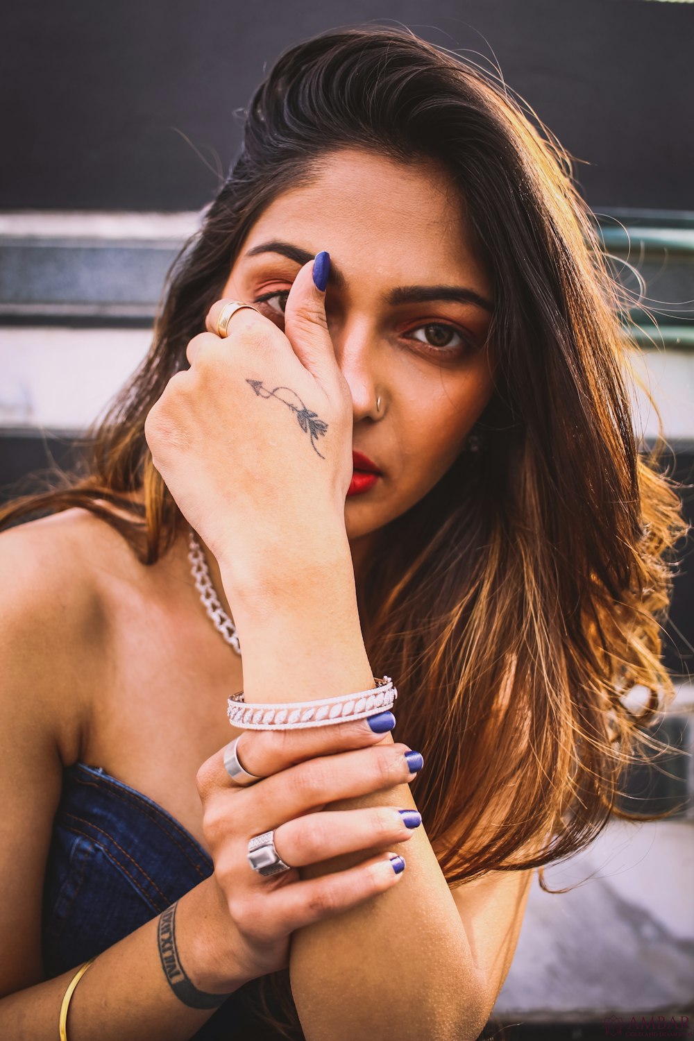 woman in blue tube top partly covering face with hand