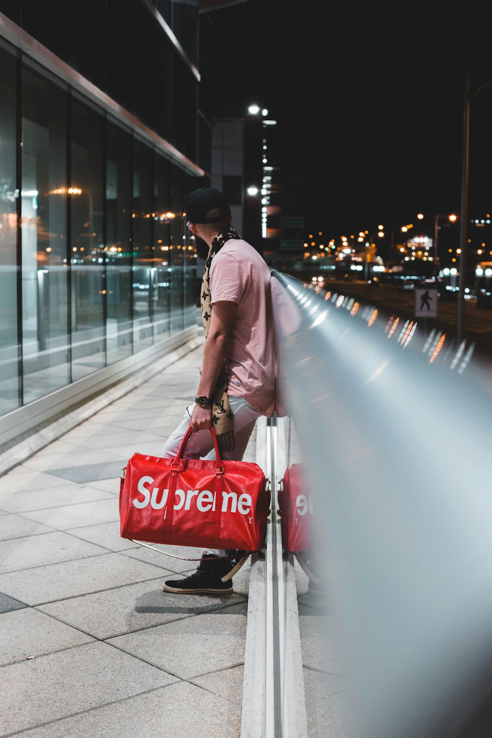 Man in pink shirt with red Supreme bag in hand walks towards building photo  – Free Clothing Image on Unsplash