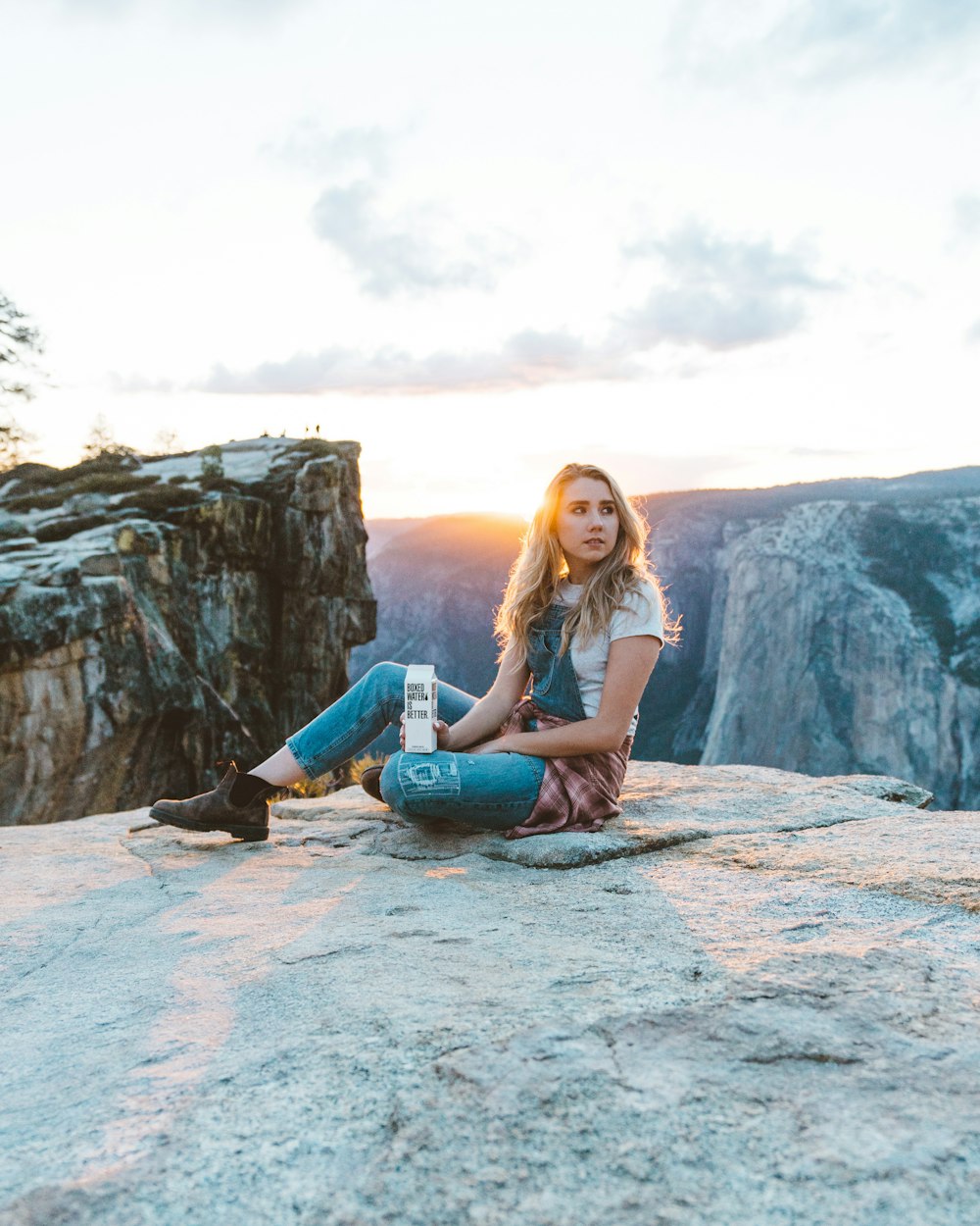 A woman sitting down in Yosemite holding a carton of Boxed Water