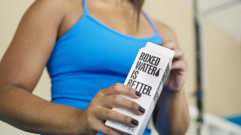 A woman holding a carton of Boxed Water while working out