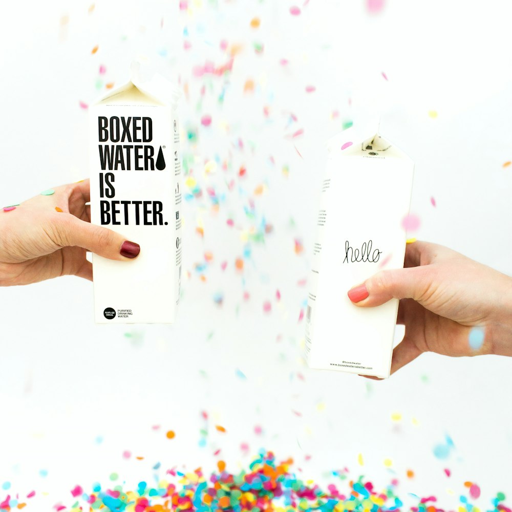 Two people holding Boxed Water cartons while confetti falls