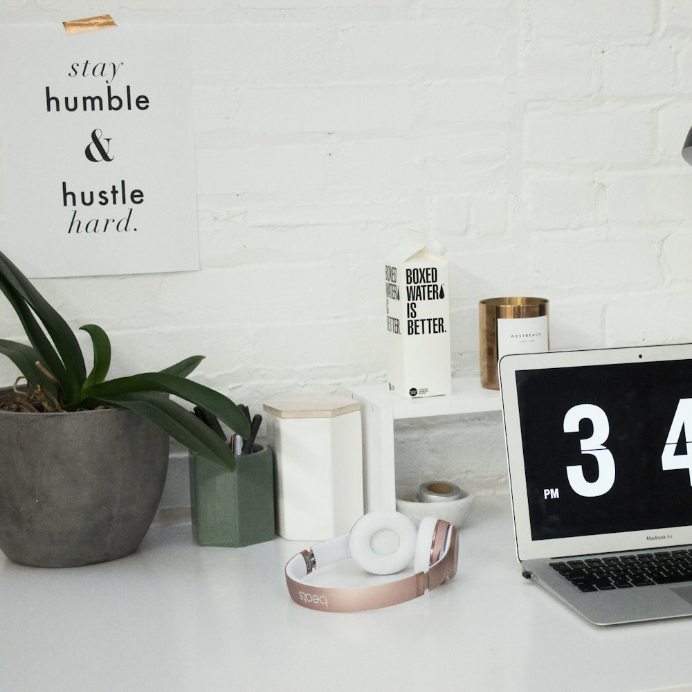 A MacBook Air sits next to headphones and a Boxed Water carton