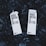 Two cartons labeled 'Boxed Water Is Better' rest on a bed of smooth, dark stones. The cartons are white and feature bold black text, emphasizing an eco-friendly message.