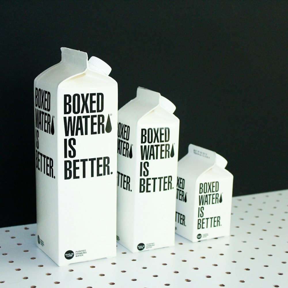 Three different sized Boxed Water cartons on a black and white background