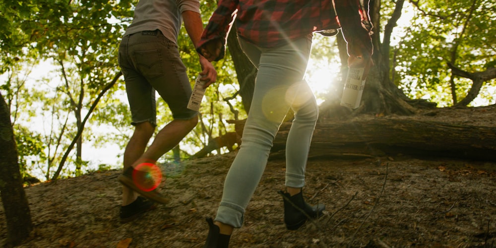 A man and woman walking in a forest holding a Boxed Water carton