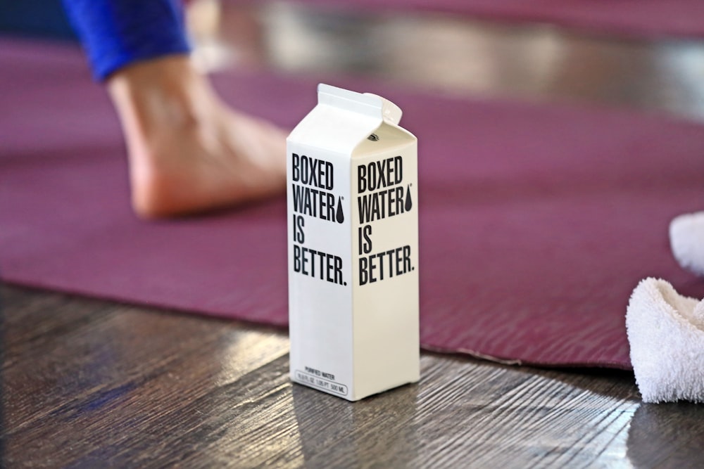 A Boxed Water carton in the foreground with a woman doing yoga in the background